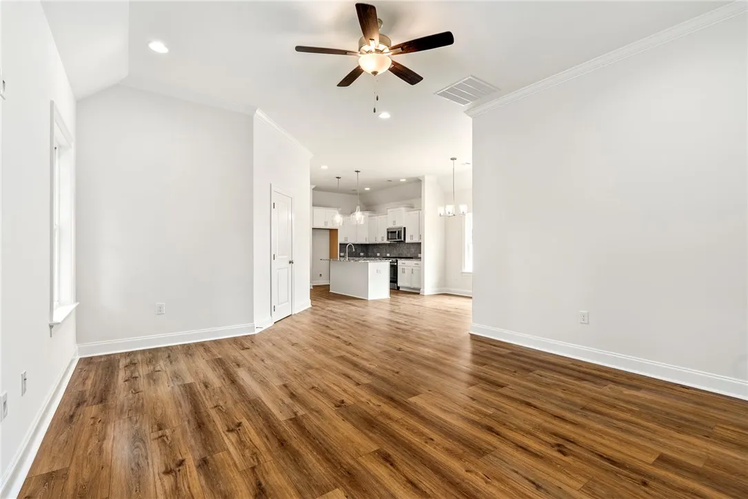Luminous open-concept living area with a kitchen island and durable hardwood-style flooring.