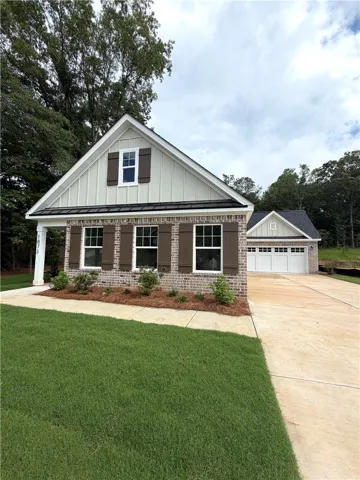 A newly constructed residence features brick and board-and-batten siding, a well-kept lawn, and an attached garage.