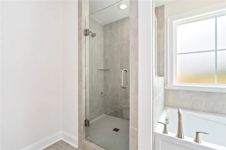 A well-appointed bathroom offers a glass-enclosed shower and a deep soaking tub by a window.