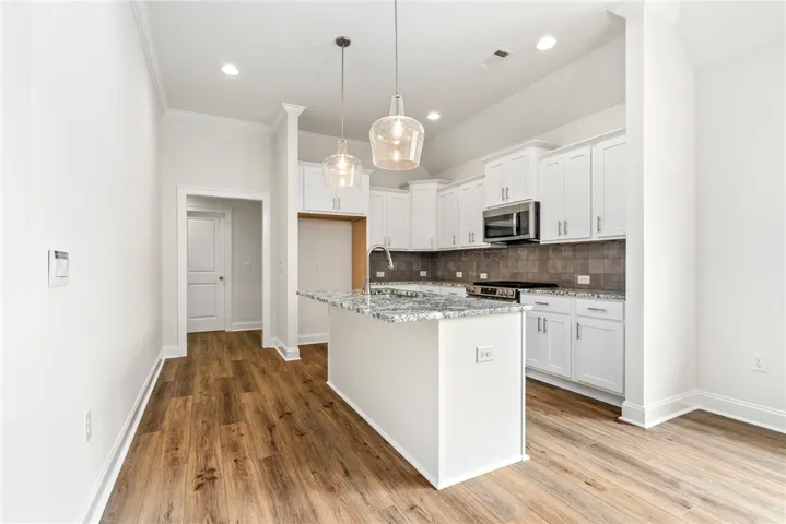 A well-lit kitchen with sleek white cabinetry, an island, and rich wood flooring.