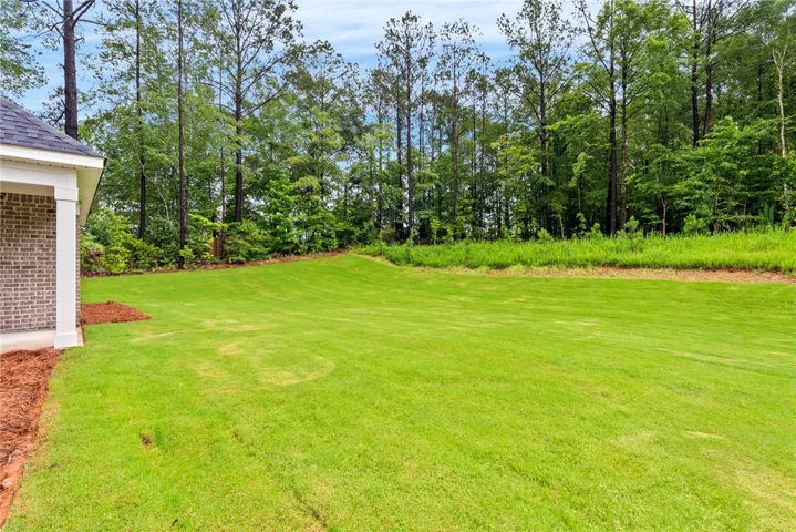 A verdant, well-maintained lawn stretches toward a lush, mature tree line.