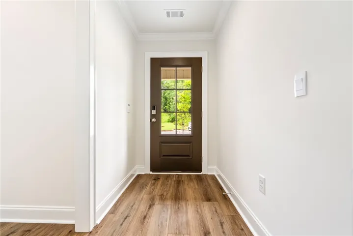 A welcoming entry hallway showcases beautiful hardwood flooring and crisp white walls.