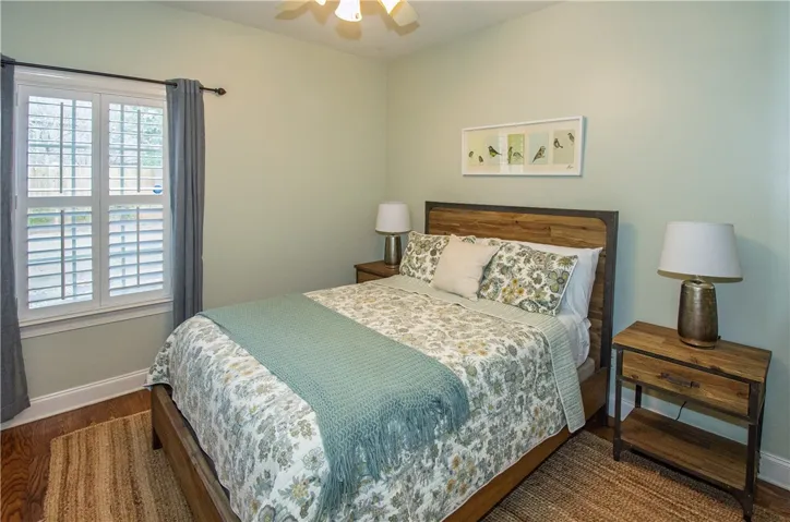 Guest bedroom with wood flooring overlooking back yard