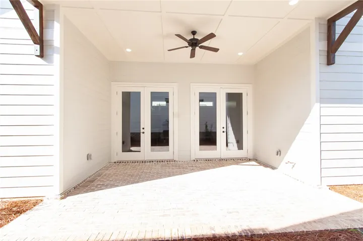 This inviting covered patio features dual French doors and a ceiling fan, perfect for outdoor relaxation.