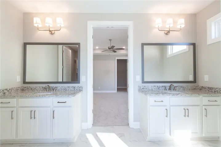 This primary bathroom features a dual vanity with granite counters and tile flooring.