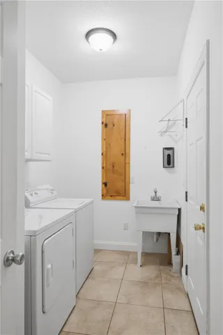 Well-equipped laundry room with a utility sink, upper cabinetry, and a dedicated closet for cleaning supplies.
