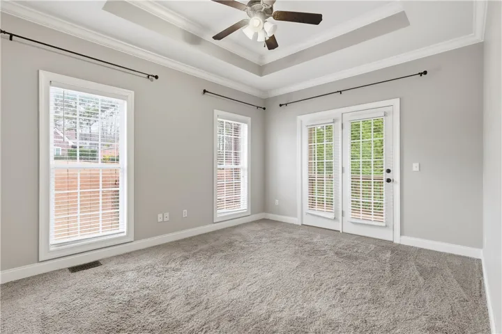 Primary bedroom with tray ceiling and French doors to the porch.