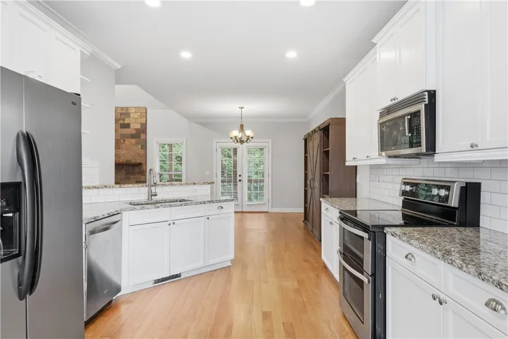 A bright, timeless kitchen featuring granite countertops, stainless steel appliances, and a classic subway tile backsplash.