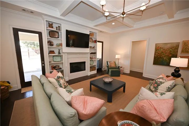 Great Room with hardwood floors & coffered ceilings, built-in and gas log fireplace.