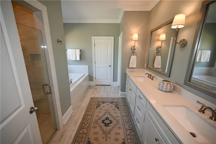 Primary bath complete with double sink extended vanity, tiled shower, soaking tub, water closet & walk in closet with structured shelving.