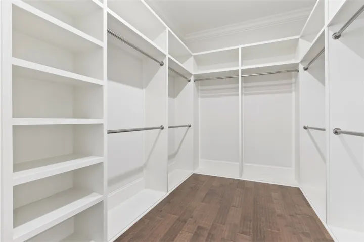A walk-in closet offers custom shelving, multiple hanging zones