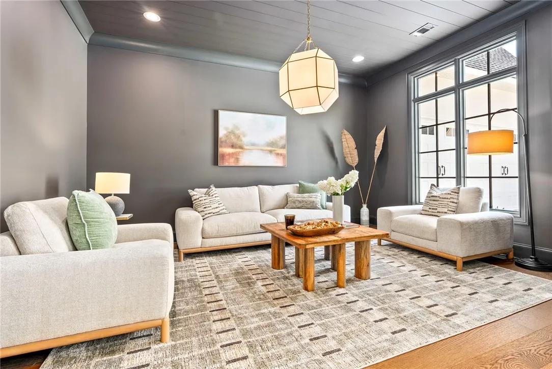 Recessed lighting illuminates this stylish living room, featuring rich hardwood floors.