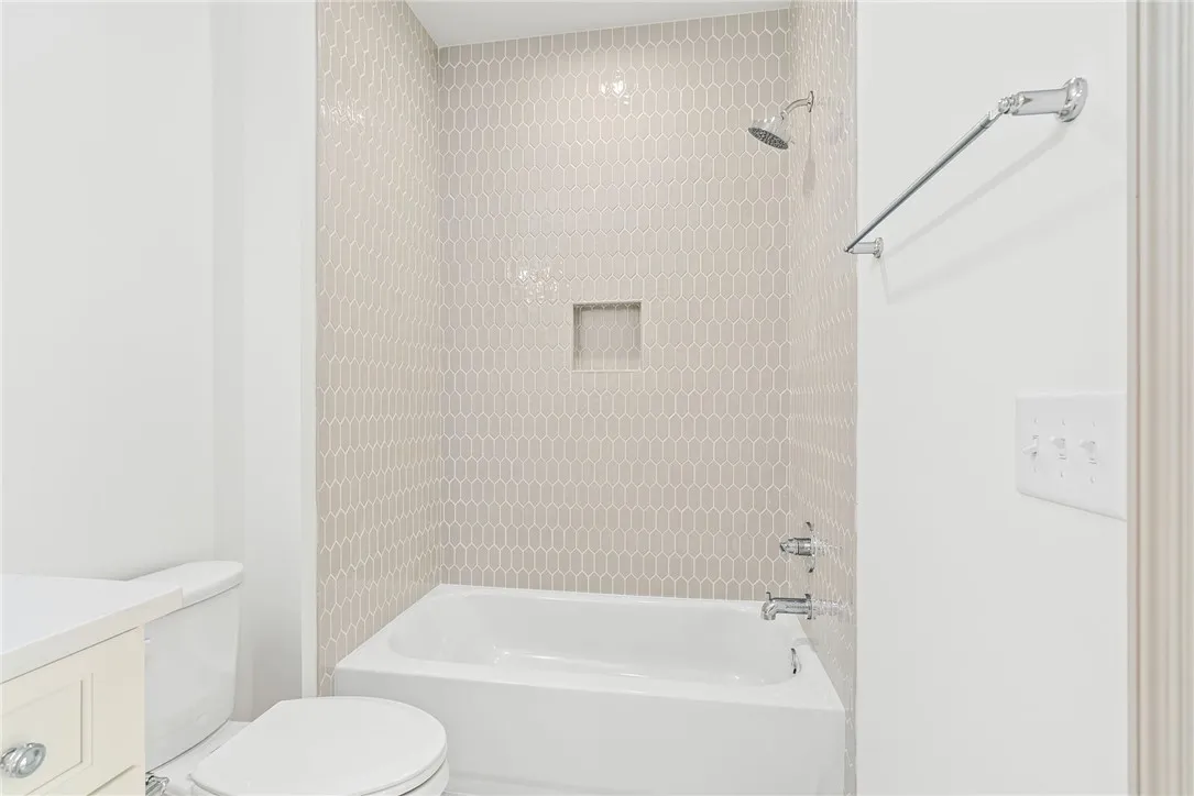 A pristine bathroom featuring a clean bathtub and shower with tasteful geometric tile.