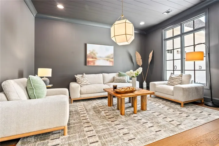 Recessed lighting illuminates this stylish living room, featuring rich hardwood floors.
