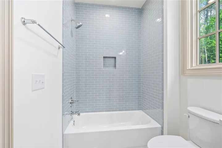 A well-appointed bathroom features a bathtub and shower with tasteful tiled surrounds.