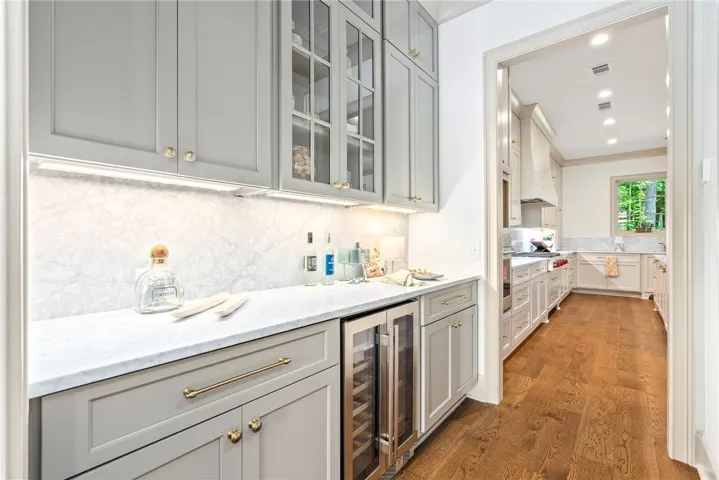 An inviting passage reveals an elegant butler's pantry with a wine cooler, leading into a well-appointed kitchen.