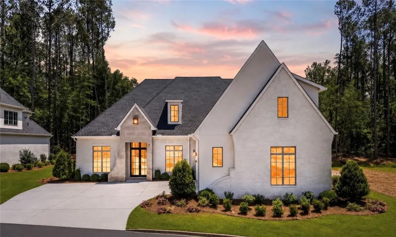 Elegant white brick residence with a gabled roofline and well-tended landscaping.