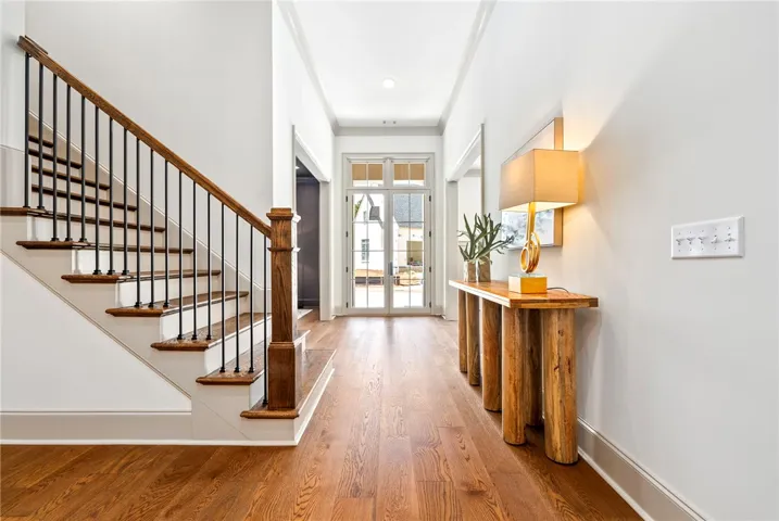 A graceful staircase with wood treads and wrought iron balusters complements the warm hardwood floors in this inviting entryway.