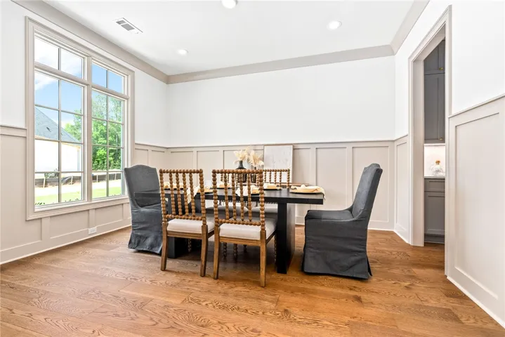 Rich hardwood flooring complements the classic wainscoting and abundant natural light from a large window.