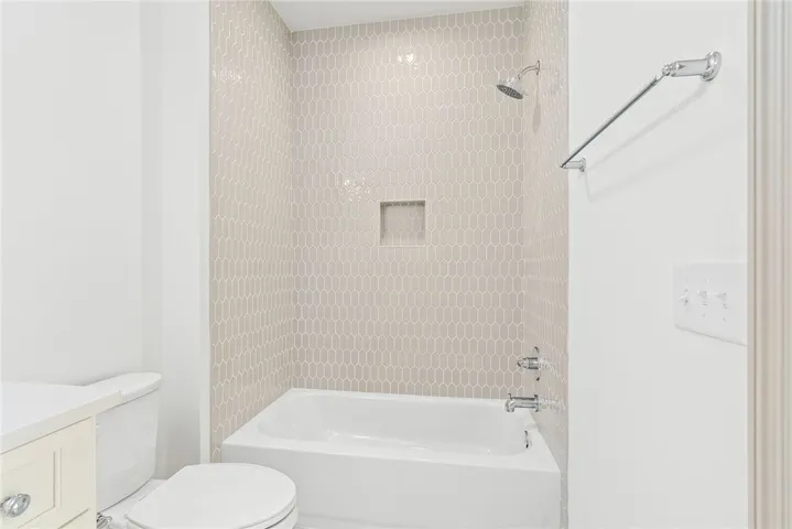 A pristine bathroom featuring a clean bathtub and shower with tasteful geometric tile.