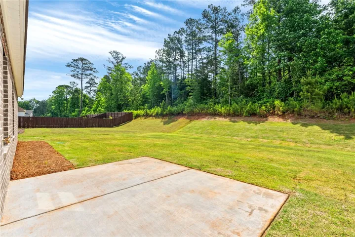 A spacious backyard with a private wooden fence and mature trees along the perimeter.