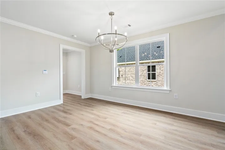 A striking modern chandelier illuminates this spacious living area with resilient wood-look flooring.