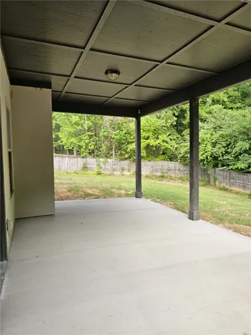 This inviting covered patio offers a serene outdoor space, perfect for relaxing and enjoying the backyard.