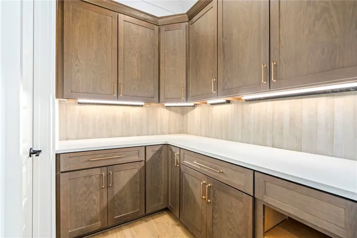 Ample storage solutions in this well-appointed pantry, featuring custom cabinetry and convenient under-cabinet lighting.