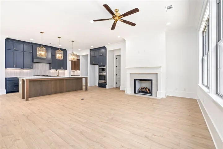 A spacious, open-concept area combines a modern kitchen with a comfortable living space, featuring a central island and a cozy fireplace.