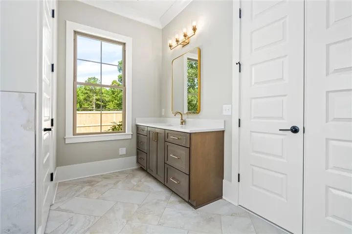 A well-appointed bathroom vanity with a spacious countertop and a generous window offering verdant outdoor​​‌​​​​‌​​‌‌​‌‌​​​‌‌​‌​‌​‌​​​‌​​ views.