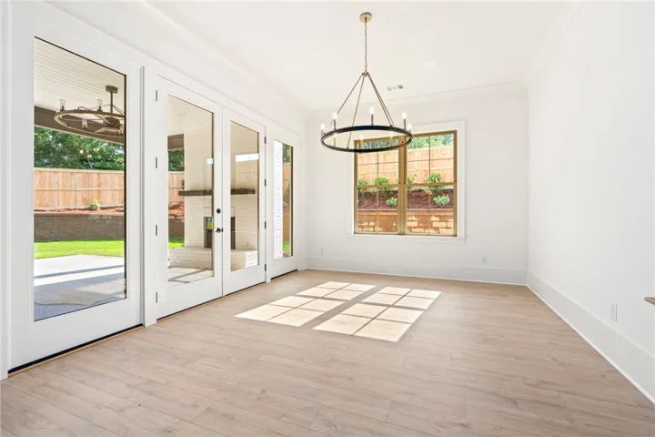A refined dining space features light wood flooring and french doors that open to the outdoor patio.