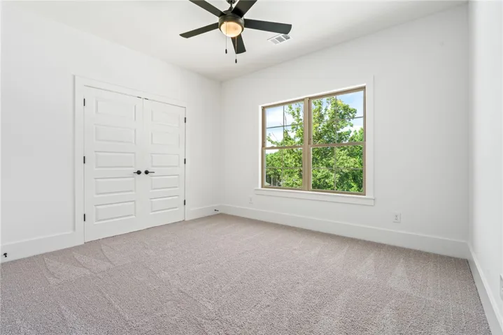 A quiet bedroom retreat with a broad window offering tranquil views of verdant trees.