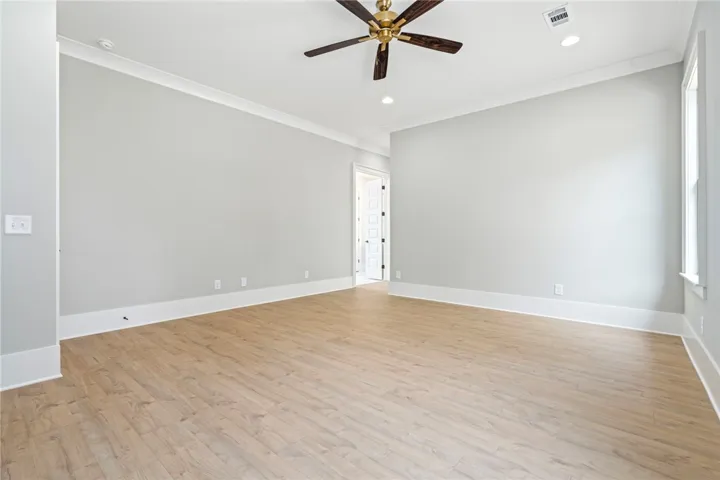A spacious room features a rich wood-blade ceiling fan and durable hardwood flooring.