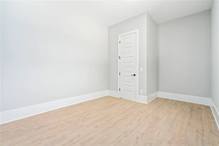 An airy bedroom with light wood flooring and crisp white trim awaits personalization.