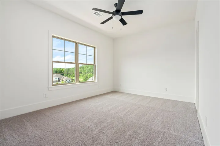 A spacious room with plush carpeting and abundant natural light from a large window.