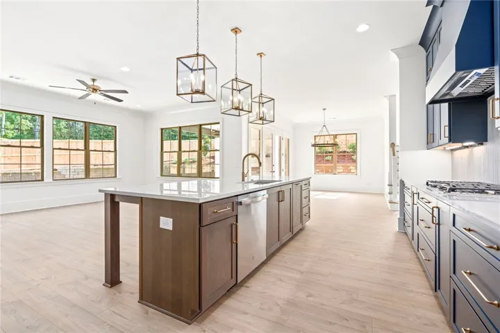 An inviting kitchen with a spacious island, pendant lights, and ample natural illumination.