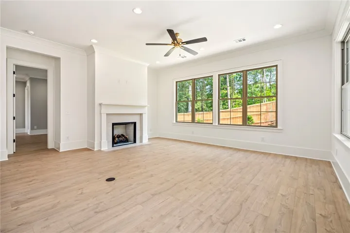 A spacious, naturally illuminated living area featuring a classic fireplace and broad views of verdant trees.