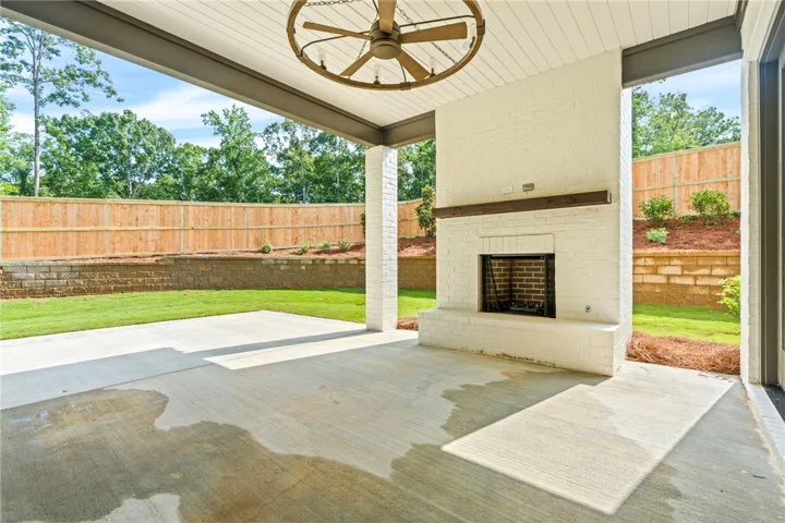 Enjoy outdoor living with a covered patio featuring a cozy fireplace and views of the private yard.