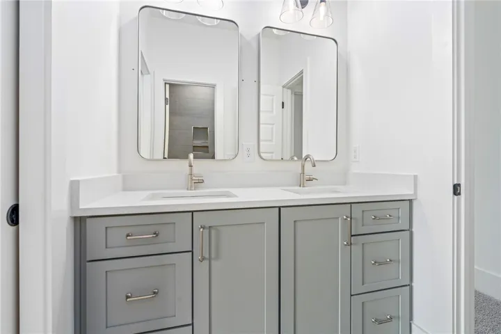 A well-appointed primary bathroom features dual sinks set in a sleek gray vanity.