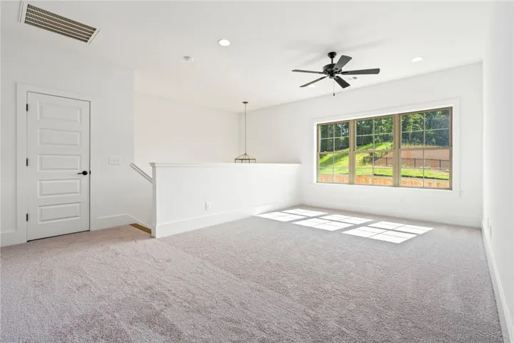 A spacious upper-level living area with abundant natural light from expansive windows.