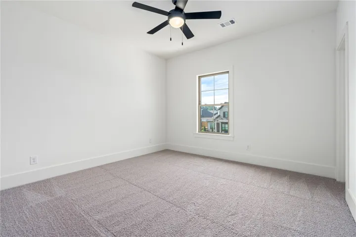 A well-proportioned secondary bedroom features plush carpeting and a serene neighborhood vista.