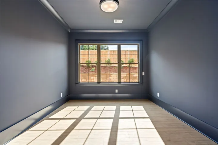 Natural light floods this versatile space, featuring refined crown molding and durable wood flooring.