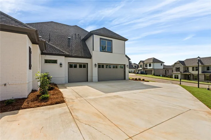 A pristine concrete driveway leads to a stylish home with modern garage doors.