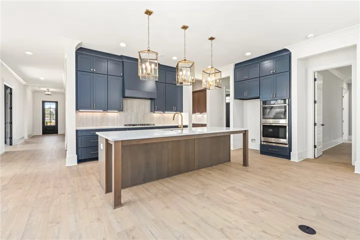 A pristine kitchen features sleek blue cabinetry and a generous center island for culinary endeavors.