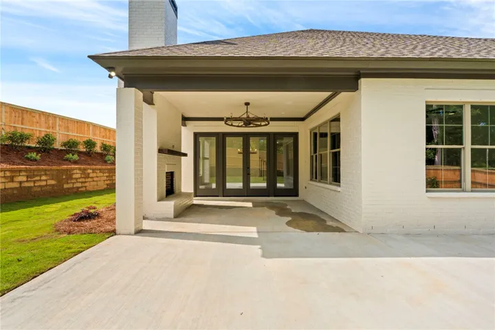 An inviting covered patio featuring a cozy fireplace and direct access to the vibrant yard.