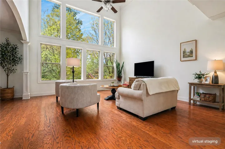 This living room features expansive windows framing picturesque outdoor views and warm hardwood flooring.