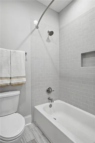 The second-floor suite functions like a second primary. The bath includes an extended vanity with dressing table, a linen closet, and a separate room for the tub/shower and toilet.