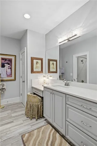 The second-floor suite functions like a second primary. The bath includes an extended vanity with dressing table, a linen closet, and a separate room for the tub/shower and toilet.