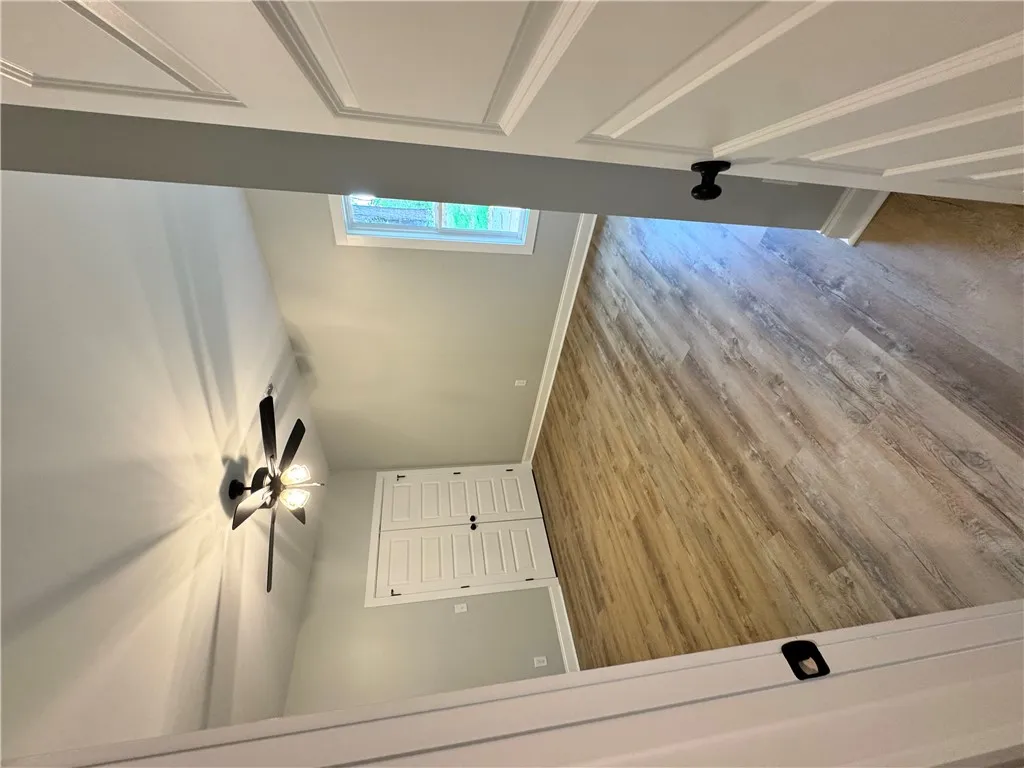 This interior hallway features beautiful wood flooring, a ceiling fan, and abundant natural light.