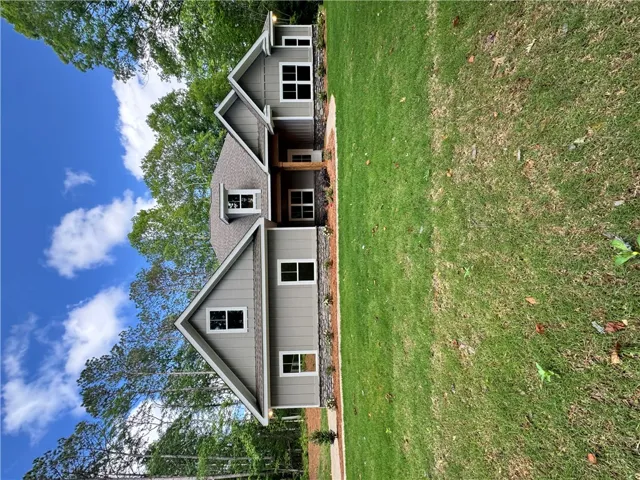 This captivating residence presents a charming exterior with a spacious yard, surrounded by lush trees.